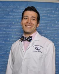 Headshot of Columbia Nursing male student with white Columbia Nursing coat.